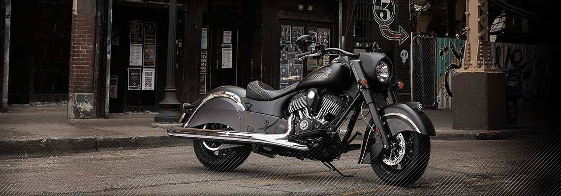 Black Indian Motorcycle® bike sitting on a concrete ground with brick pillars and a fence behind it